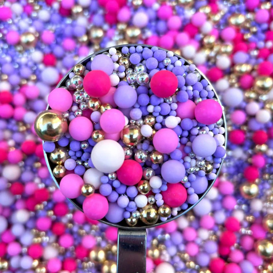 Spoon filled with colorful sprinkles against a background of more sprinkles.